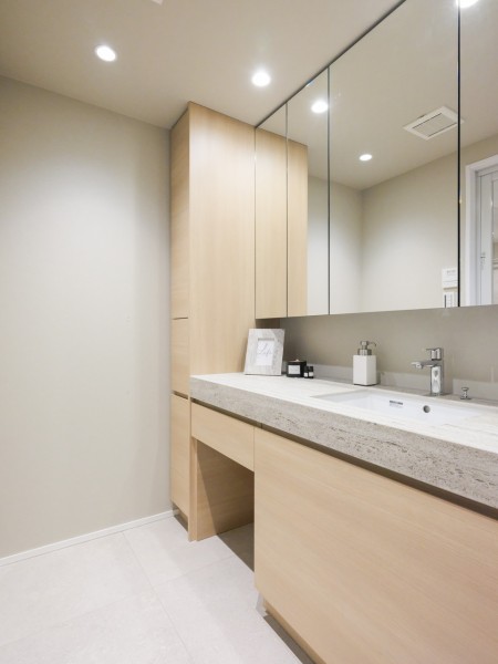 洗面台も田中工藝社製のこだわりの仕様です。クロスとフロアー材と調和した色合いで、落ち着いた雰囲気の空間となっております。収納棚も設置しており、リネン類やストックの日用品の収納にも便利です。