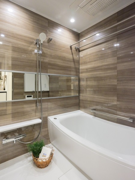 光沢のある木目調パネルが高級感を漂わせるバスルームです。ワイドミラーがより空間を広く感じさせる、ゆったりとしたリラクゼーション空間です。