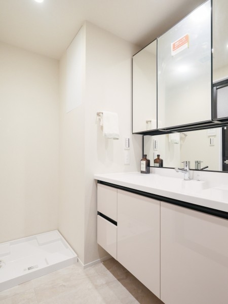 白を基調とした清潔感溢れるデザインの洗面化粧台です。こまごまとした物が多くなりがちな洗面室には、埋込棚や洗面化粧台の三面鏡裏、足元のキャビネットなど収納スペースをたっぷり確保しています。