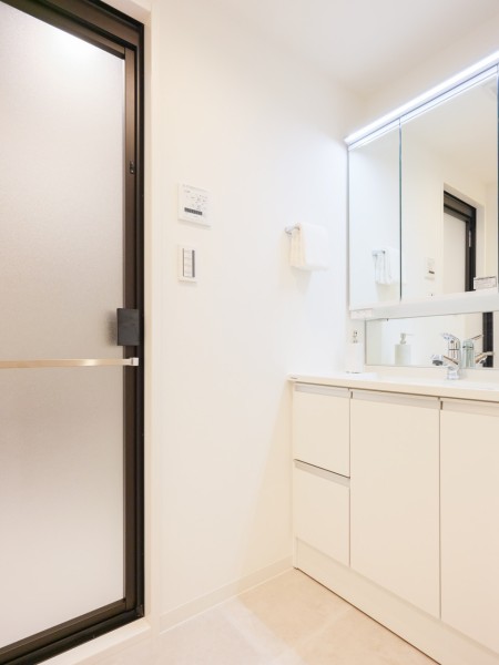 白を基調とした清潔感溢れるデザインの洗面化粧台です。三面鏡の裏側や足元のキャビネットなど、収納豊富で実用的な洗面空間です。