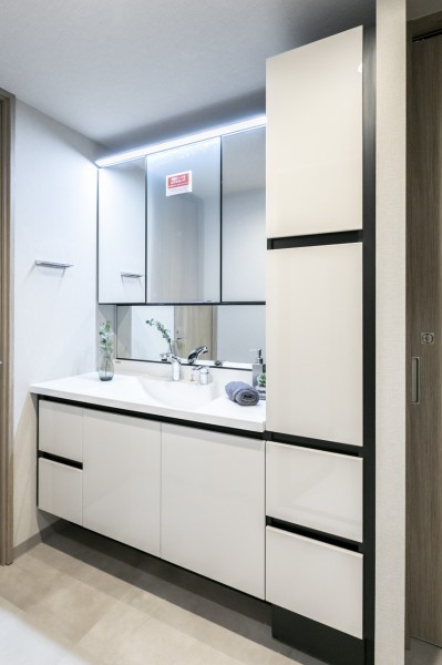 三面鏡にキャビネットと大容量の収納を備えた洗面台です。隣にはトールキャビネットを備え付けましたので、リネン類や洗剤類のストックなども収納でき、整頓された空間を保てます。