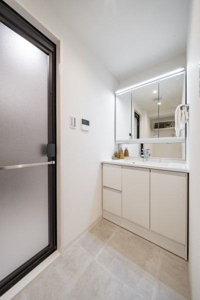 白を基調とした清潔感溢れるデザインの洗面化粧台です。三面鏡の裏側や足元のキャビネットなど、収納豊富で実用的な洗面空間です。