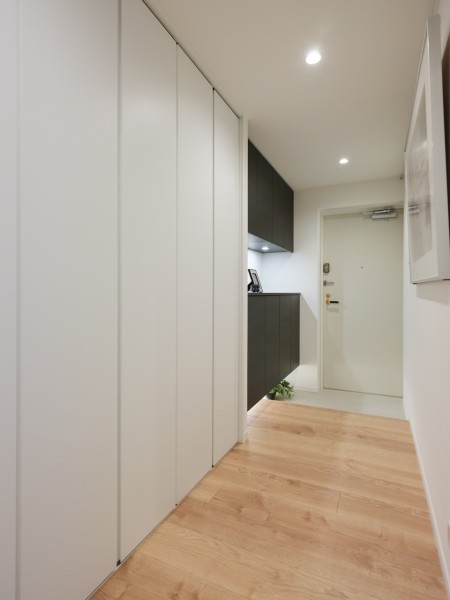 フットライトからのびる光が足元を優しく包み込む気品溢れる玄関です。ゆとりのある廊下には収納を備え付けました。