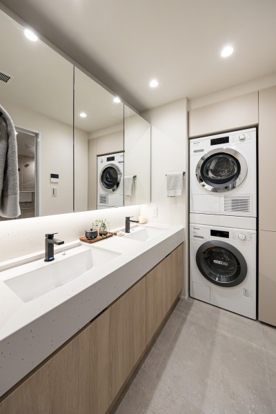 お部屋の内装と統一された、清潔感漂う田中工藝製の２ボウル洗面化粧台です。洗面化粧室にもMiele製のビルトイン洗濯機を備え付けました。