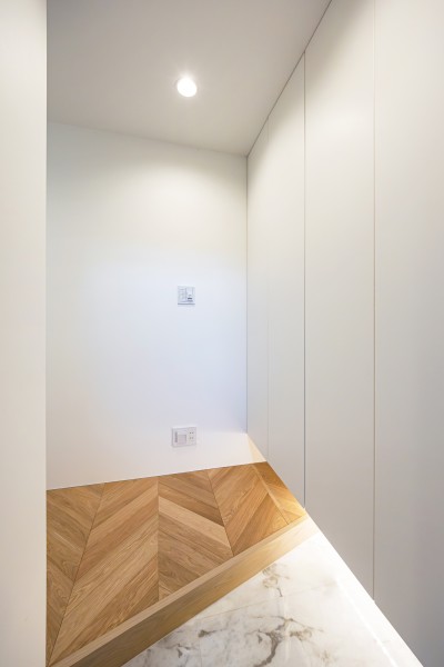 玄関の框を斜めにデザインすることで空間を広く見せた玄関設計です。​収納豊富なシューズボックスの下にはフットライトを設置し、気品が溢れる玄関に仕上げました。​