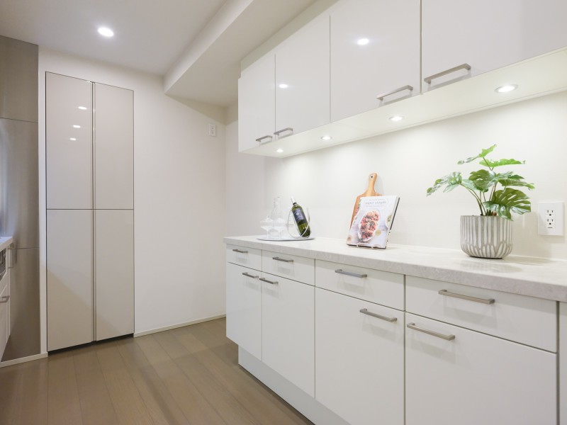 キッチン背面には同じ色調のカップボード、ゆとりあるカウンタースペースを備えています。奥にはパントリーが配備され、散らかりがちなキッチン用品もすっきりと収納いただけます。