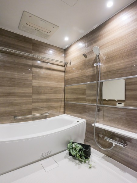 光沢感があり、落ち着いた雰囲気の木目調のパネルを採用したバスルームです。リラックスしやすく、心地よくバスタイムを過ごせそうです。