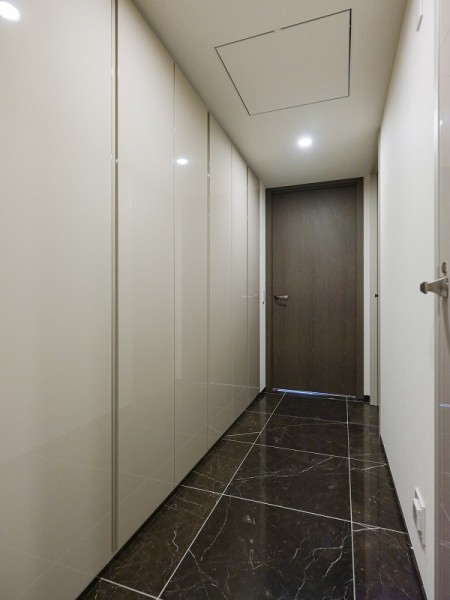 玄関と同じ石調タイルが敷設された廊下には容量のある収納を備え付けました。日用品のストックに重宝しそうです。