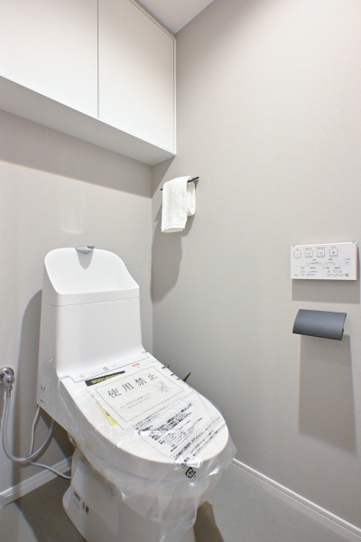 ウォシュレット一体型のトイレは、お掃除の手助けをしてくれる便利機能が搭載されています。上部には収納に便利な吊戸棚を備え付けました。