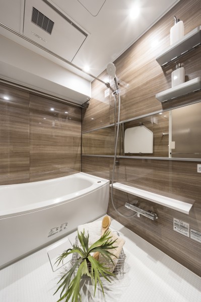 光沢のある木目調パネルが高級感を漂わせるバスルームです。ワイドミラーによって実際より広く感じられるくつろぎの空間です。