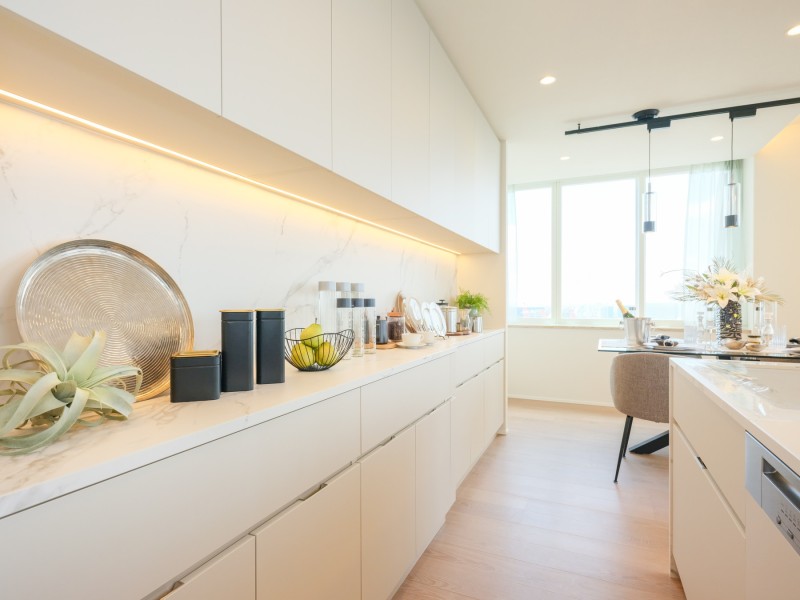 背面には色味を揃えた収納豊富なカップボードを備え付けました。石調デザインを取り入れたカウンタートップを間接照明が照らし、ハイグレードな住まいにふさわしい上質な空間へと演出してくれます。