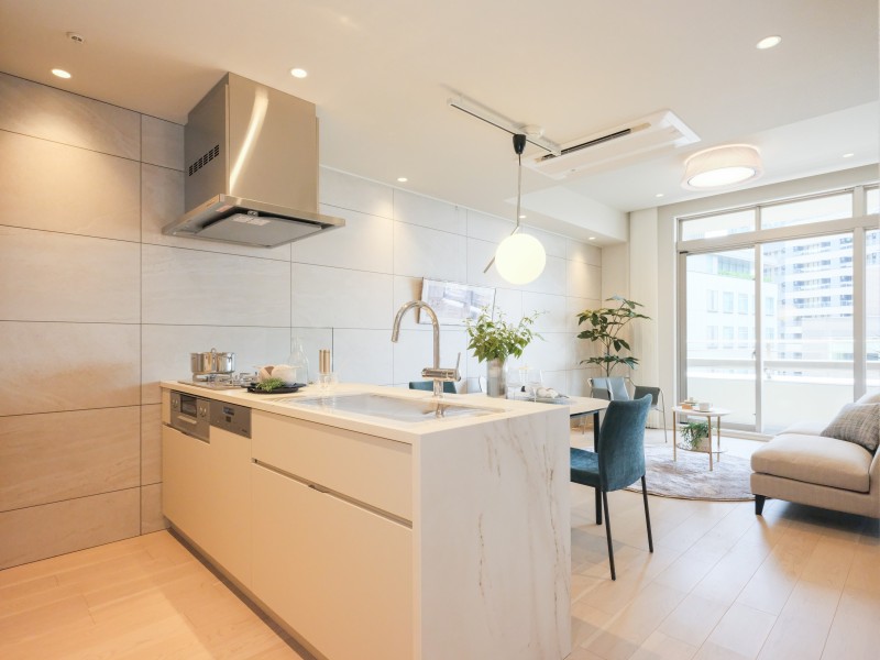 お部屋の雰囲気と調和する、田中工藝製オリジナルキッチンです。面材はグレーベージュの柔らかな色合いが美しく、家事時短に便利な食洗器や三口コンロを搭載しています。