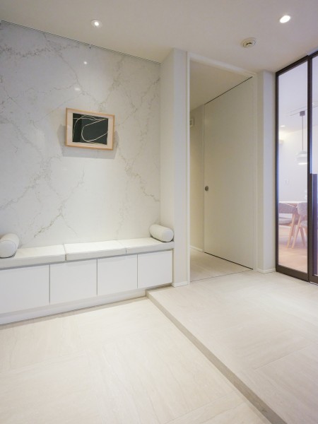 大理石調の壁が高級感を演出する、洗練された玄関スペース。ベンチタイプのシューズボックスを配置し、ブーツや革靴などの着脱時に腰掛けられるような造作に仕上げました。