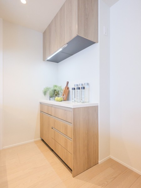 キッチンの背面にはシステムキッチンとお揃いのデザインのカップボードが設置されております。吊戸棚と足元に収納棚があり、食器や調味料など様々なものを収納することができます。