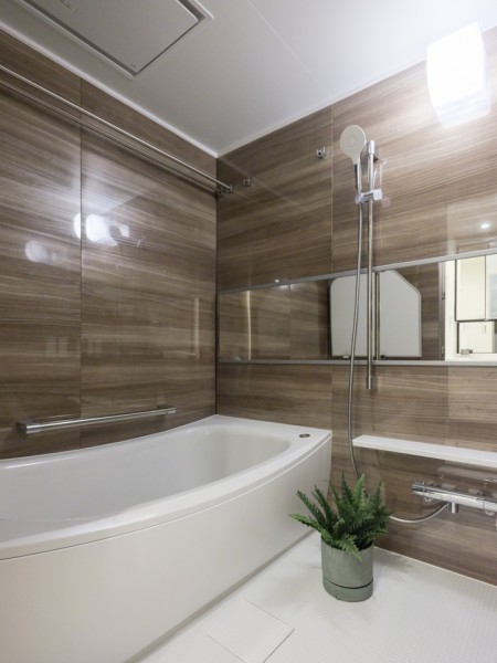 木目調パネルが施されたゆったりとしたバスルームです。ワイドミラーがより広く空間を感じさせ一日の疲れをしっかりと癒す、上質なリラクゼーションタイムをお楽しみいただけます。