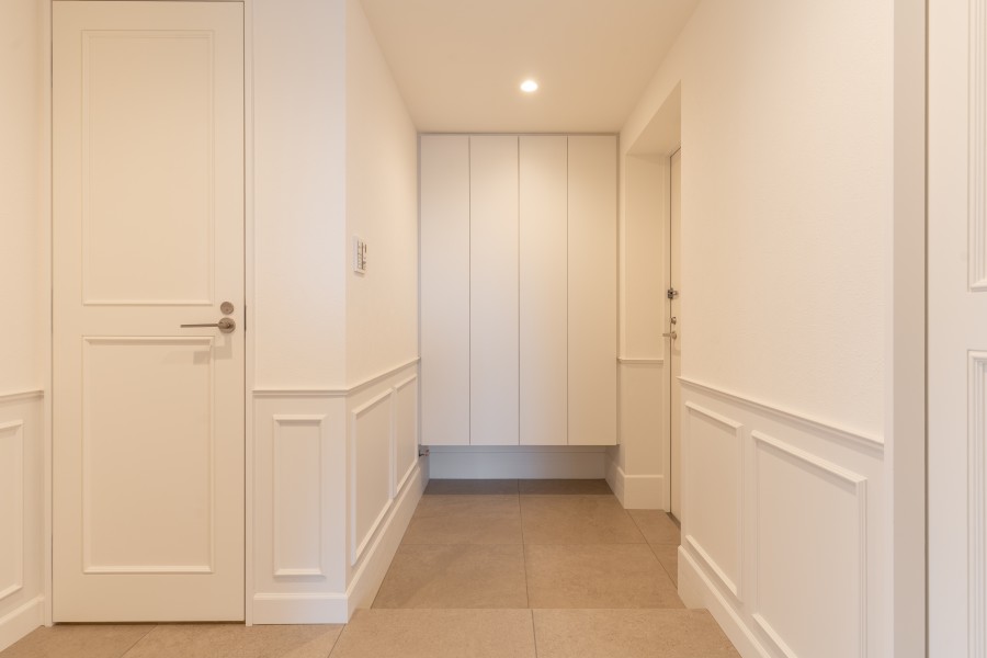 玄関には高さのあるシューズボックスを設置いたしました。フットライトとダウンライトがあり、いつでも安心して利用できるようになっております。廊下と統一された内装となっております。