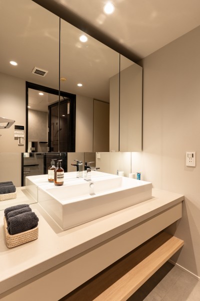 洗面化粧台は大きな鏡があり身支度が捗ります。お部屋の雰囲気と調和するように色数を少なくし、シックな雰囲気となっております。身支度グッズを三面鏡裏に収納できます。