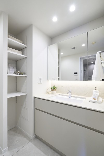 空間にやさしく溶け込むデザインの洗面化粧台は、収納力に優れた三面鏡タイプです。隣には収納棚を設置し、身支度や洗濯まわりのアイテムもすっきり整理できます。