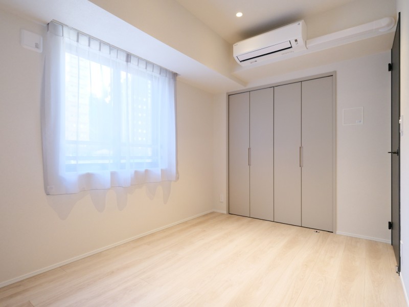 約5.0帖の洋室1です。温もりを感じるフローリングや、ホワイトで統一された壁紙が柔らかい雰囲気を演出する伸びやかな空間です。