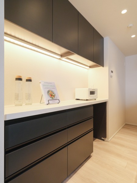 キッチンの背面にはシステムキッチンとお揃いのデザインのカップボードが設置されております。吊戸棚と足元に収納棚があり、食器や調味料など様々なものを収納することができます。