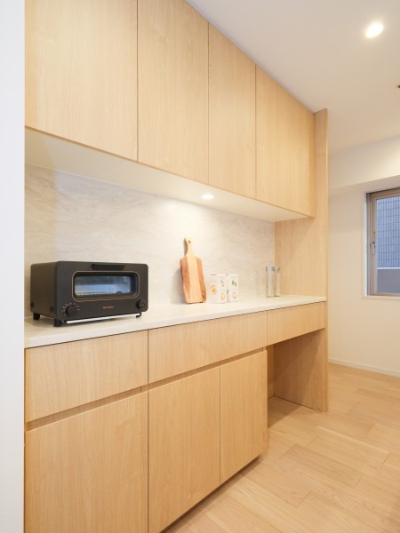 キッチンの背面にはシステムキッチンとお揃いのデザインのカップボードが設置されております。吊戸棚と足元に収納棚があり、食器や調味料など様々なものを収納することができます。