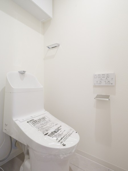 ウォシュレット一体型のトイレは、お掃除の手助けをしてくれる便利機能が搭載されています。上部には収納に便利な吊戸棚を備え付けました。