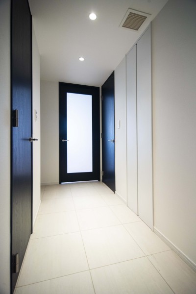 LDKへと続くホールは、明るい色合いでまとめられ、ブラックの建具がアクセントになっている空間です。ガラス扉からやわらかな光が届き、明るさとほどよい抜け感が感じられます。