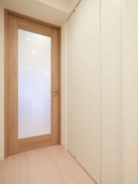 リビングへと続く扉には、透明感あふれるガラス戸を採用しました。視線の抜けを作ることで、廊下まで自然光が届く開放的な住まいです。