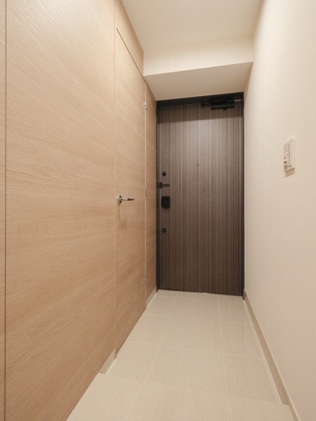 明るい木目の建具と温かみのあるアイボリーのタイルが調和する玄関です。人感センサー照明のため帰宅時に暗闇の中手探りでスイッチを探す必要がなく、明るい空間が出迎えてくれます。