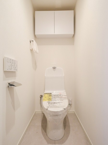 シンプルで安らぎが宿るレストルームです。吊戸棚にはトイレットペーパーや掃除用具を収納でき、生活感を抑えたすっきりとした空間を実現します。