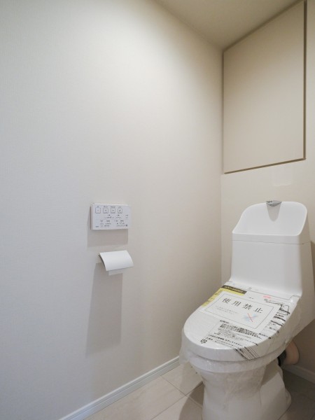 TOTO製の洗浄便座付きトイレへ新規交換し、清潔感のある空間へ整えました。背後にはペーパーや清掃用品をすっきりと収納できるスペースを設けています。壁面や床のクロスも貼り替えて明るい印象です。