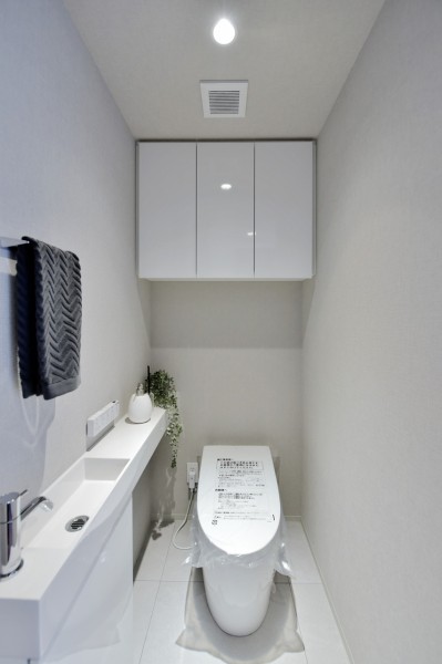 TOTO製タンクレストイレを採用しました。毎日使う場所なのでスタイリッシュでシンプル、清潔感のある空間に仕上げました。吊戸棚があり、小物類の収納に便利です。