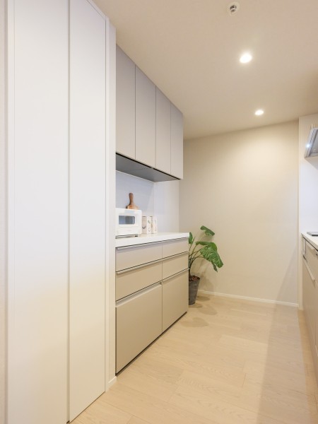 キッチン裏には同じカラーのカップボードがあります。内装と同じように淡い色彩で温かく優しい気持ちにさせます。多数の棚があるため調味料や食器などキレイに収納可能で、整理整頓することができます。