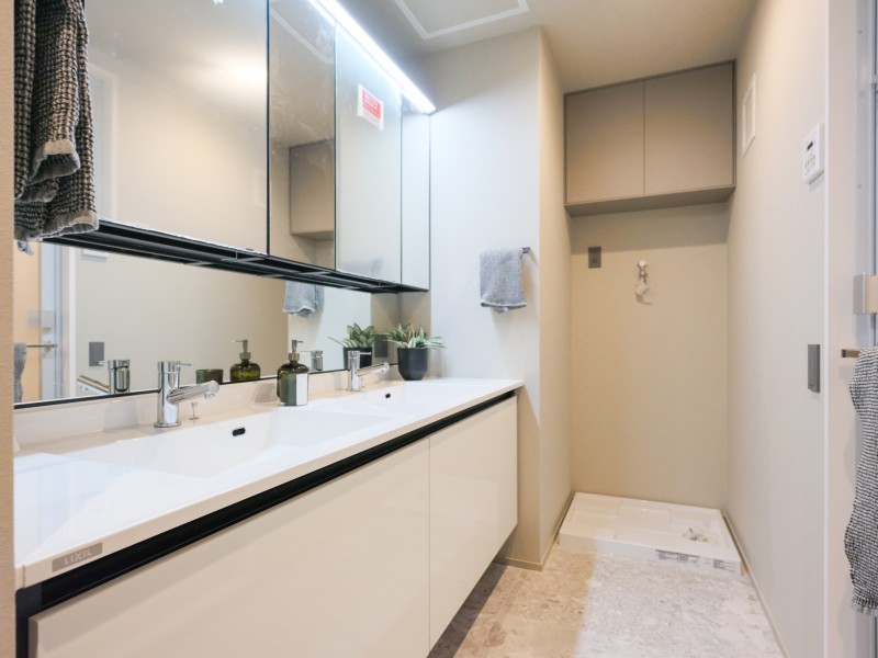 洗面化粧台は、便利なダブルボウル仕様。三面鏡の裏側や足元のキャビネットなど、収納豊富なので空間を綺麗に保てます。身支度の時間をも快適に彩る、美しく空間に溶け込む洗面化粧台です。