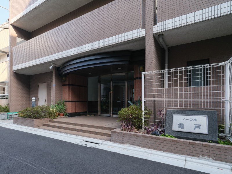 落ち着いた色調のタイル貼りの外観と、手入れの行き届いた植栽が出迎えてくれるエントランスです。