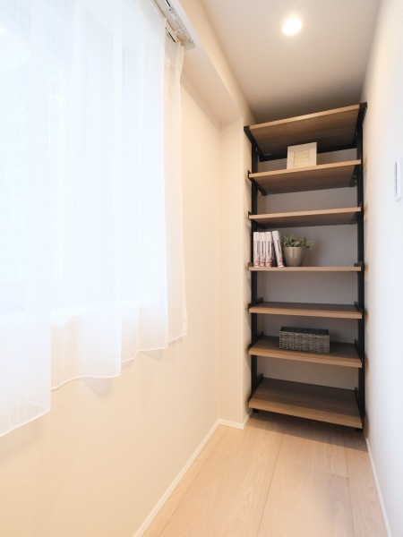 洋室1には収納に便利なアイシェルフを備え付けました。木目調の棚板とブラックのフレームが空間を引き締める、インテリアに馴染む見せる収納です。