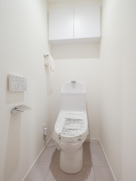 シンプルで安らぎが宿るレストルームです。吊戸棚にはトイレットペーパーや掃除用具を収納でき、生活感を抑えたすっきりとした空間を実現します。